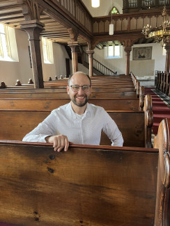 Pfarrer Thomas Bartolf in hellem Hemd in Kirchenbank St. Peter und Paul Kirchfarrnbach
